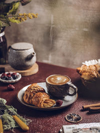 A cup of coffee with croissant in plate