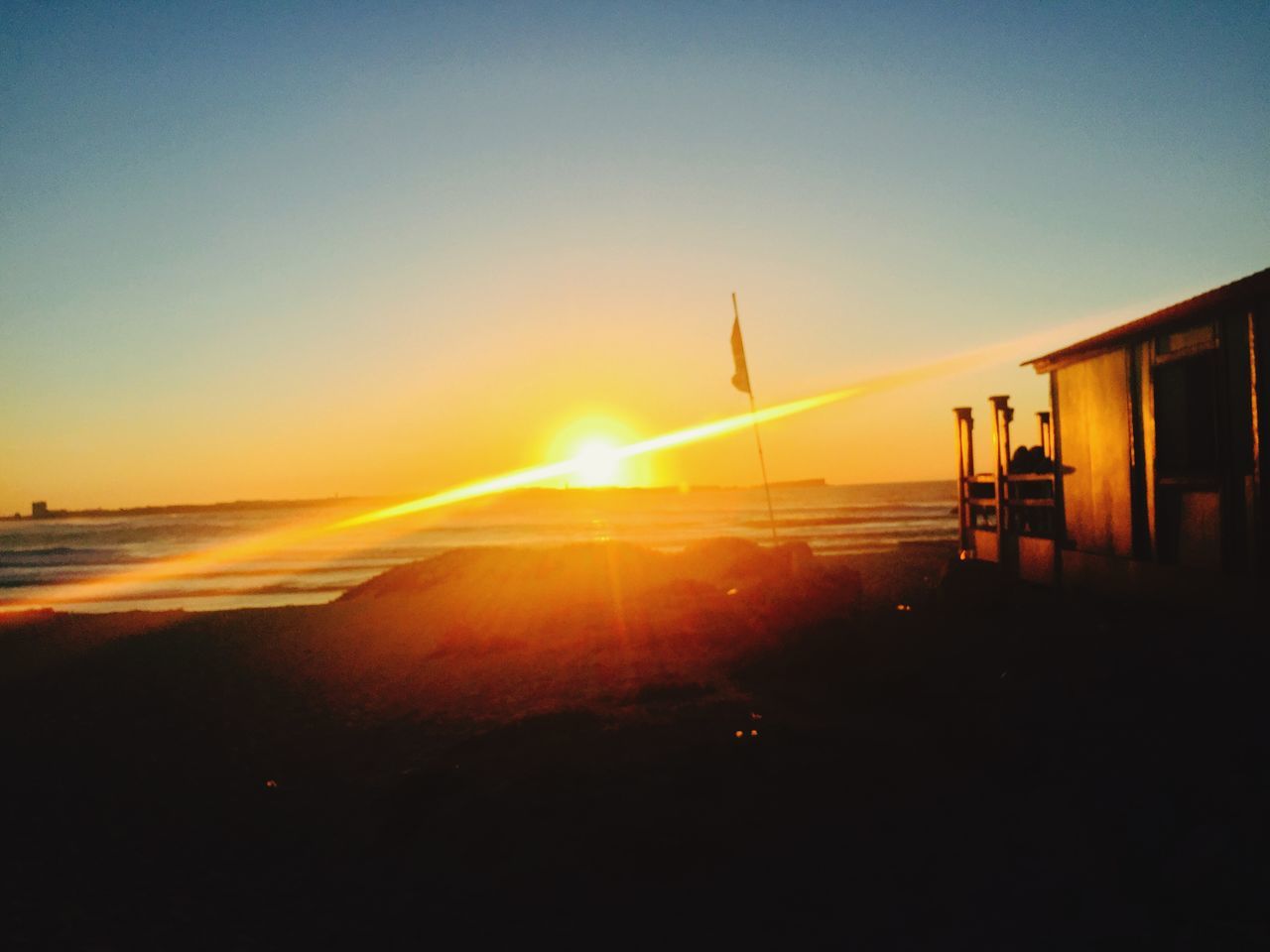 sunset, sun, sea, water, silhouette, beach, scenics, horizon over water, beauty in nature, sunlight, tranquil scene, sunbeam, sky, tranquility, clear sky, copy space, shore, built structure, nature, idyllic