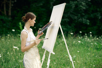 Woman holding umbrella while standing on field