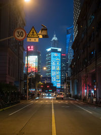 City street amidst buildings against sky at night