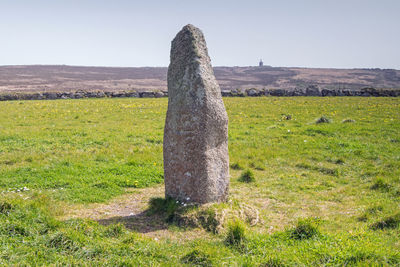 Stone wall on field against clear sky