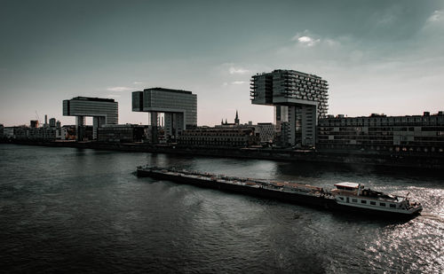 Buildings by river against sky in city