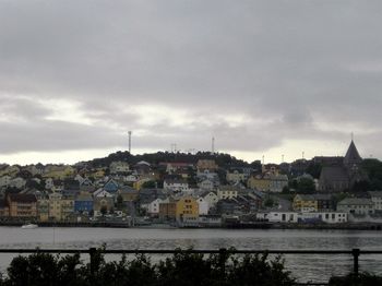 River and buildings against cloudy sky