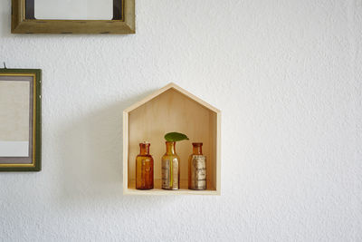 Low angle view of bottles on shelf against wall