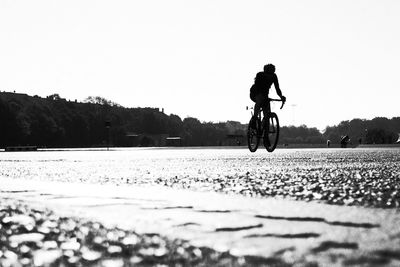 Man riding bicycle on road against sky