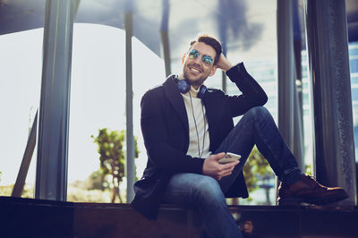 Young man sitting on window