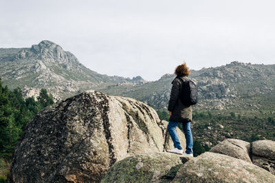 Rear view of woman standing on rocks against clear sky