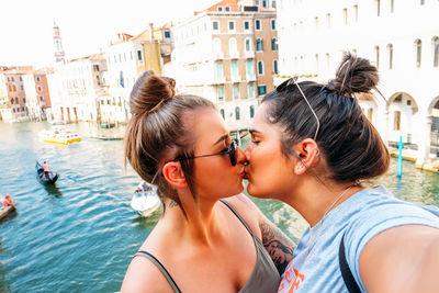 Lesbian couple kissing against buildings