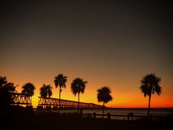 Silhouette palm trees on beach against sky during sunset