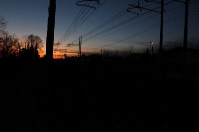 Silhouette of electricity pylon at sunset