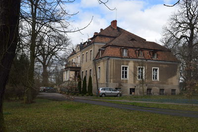 Houses by building in city against sky