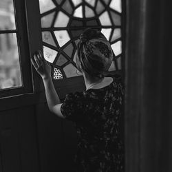 Rear view of woman standing by window