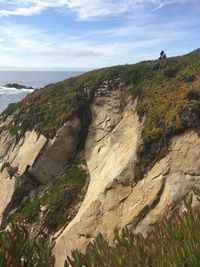 Scenic view of rocks by sea against sky