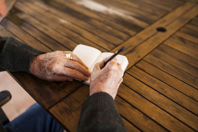 Elderly man writing in his notebook on the porch of his house