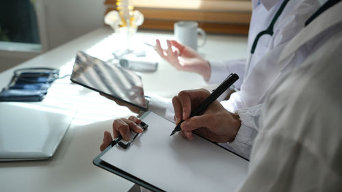 Midsection of woman using mobile phone on table