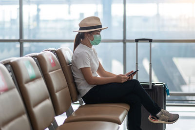 Man using mobile phone while sitting on seat at airport