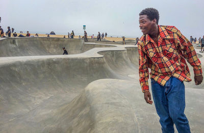 Man standing on skateboard in park against sky