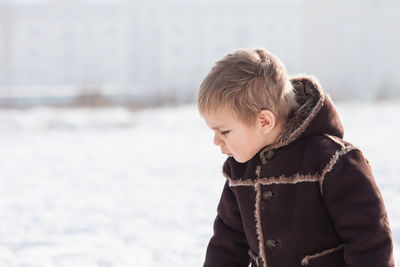 Boy looking at snow during winter