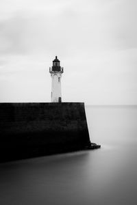 Lighthouse by sea against sky