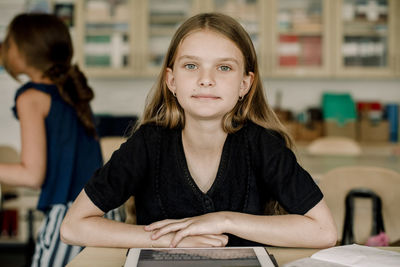 Portrait of female student with digital tablet sitting in classroom