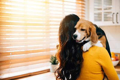 Rear view of woman with dog at home