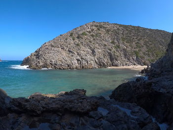 Scenic view of sea and rocks against clear blue sky sardegna cala donestica