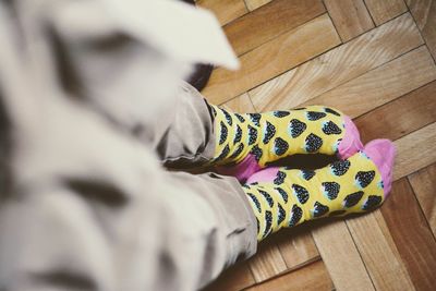 Low section of woman wearing canvas shoes on hardwood floor