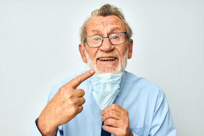 Portrait of senior man wearing mask gesturing against white background