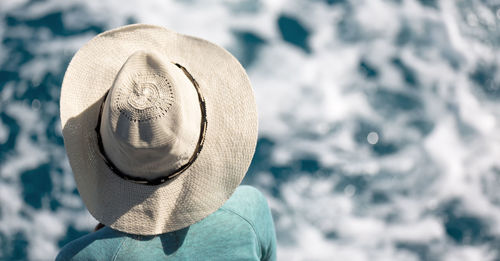 Rear view of person wearing hat against sea