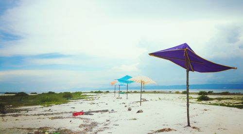 Deck chairs on beach against sky