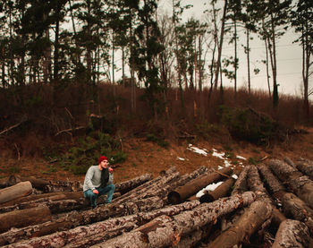 Man sitting on log in forest