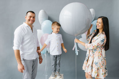 Gender reveal party. stylish beautiful family with a baby pop a balloon to find out the gender