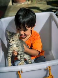 Portrait of cute boy sitting with cat in container