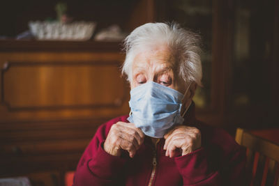 Close-up of woman wearing mask sitting at home