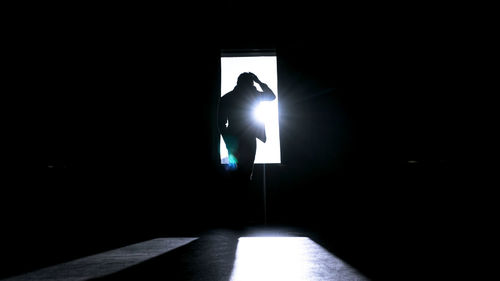 Silhouette man standing in illuminated room