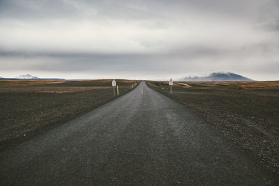 Road leading towards mountains against sky