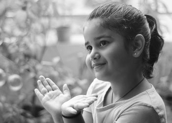 Close-up of smiling girl gesturing while looking away at park