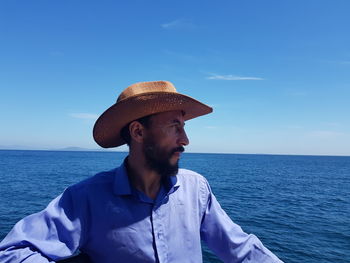Man looking at sea against blue sky