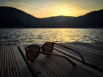 Close-up of boat on lake against sky during sunset