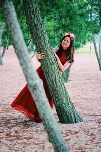 Portrait of young woman against tree trunk