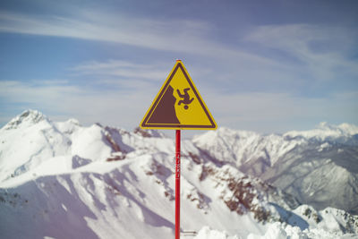Sign on background of mountains. sign warning of danger of falling. triangle on stick. 
