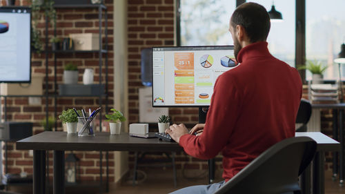 Rear view of businessman using desktop pc at office