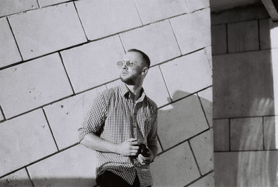 Young man looking away against wall