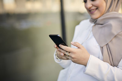 Woman using cell phone, mid section