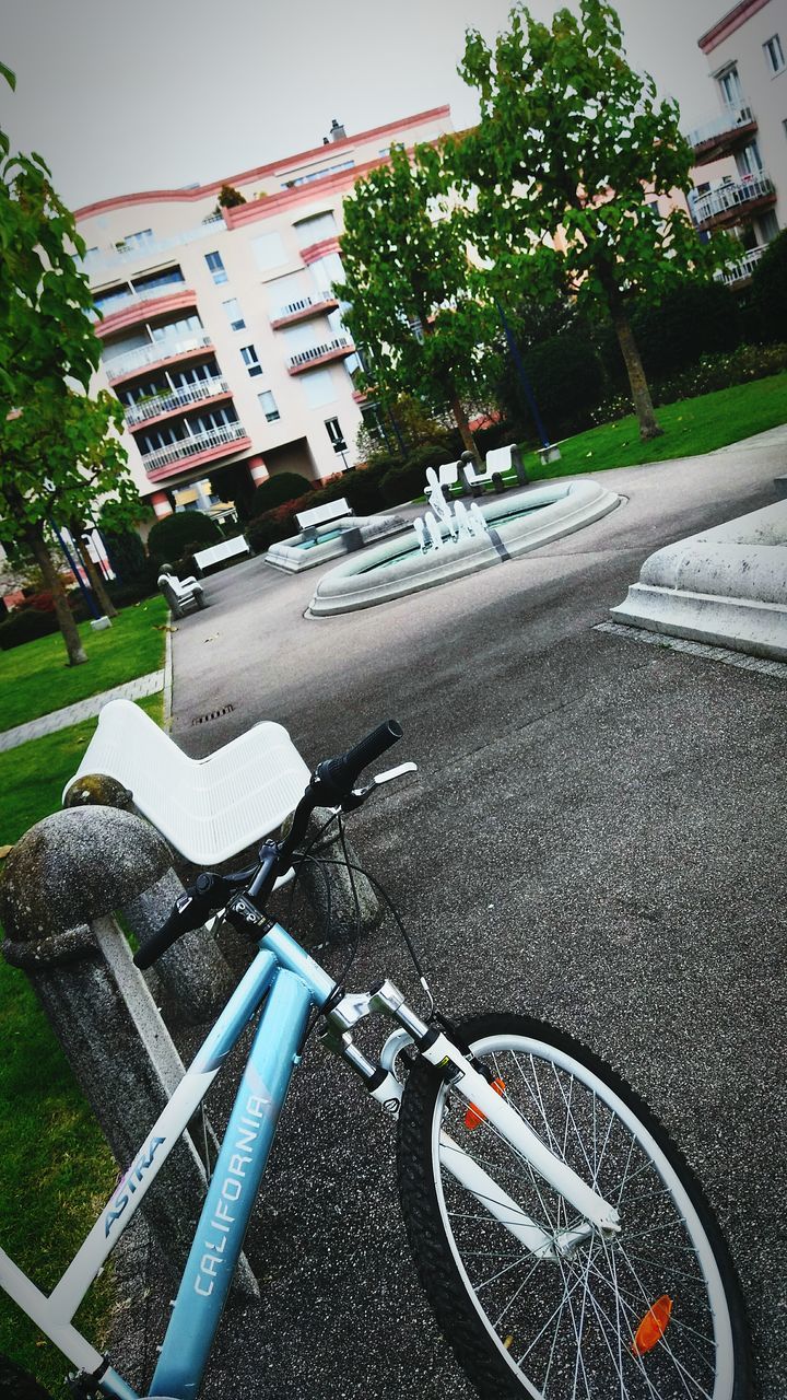 CROPPED IMAGE OF BICYCLE ON ROAD AGAINST BUILDINGS