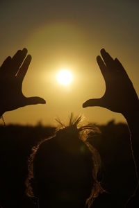 Close-up of silhouette hand against sky during sunset