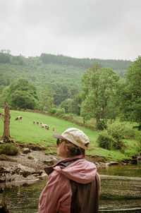 Rear view of woman standing in field with cows