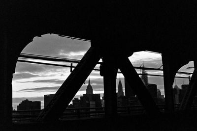 Low angle view of silhouette bridge against sky in city
