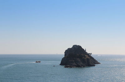 Rock formations in sea against clear blue sky