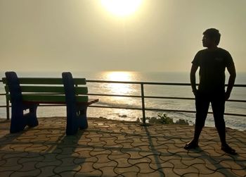 Man standing on beach against sky during sunset